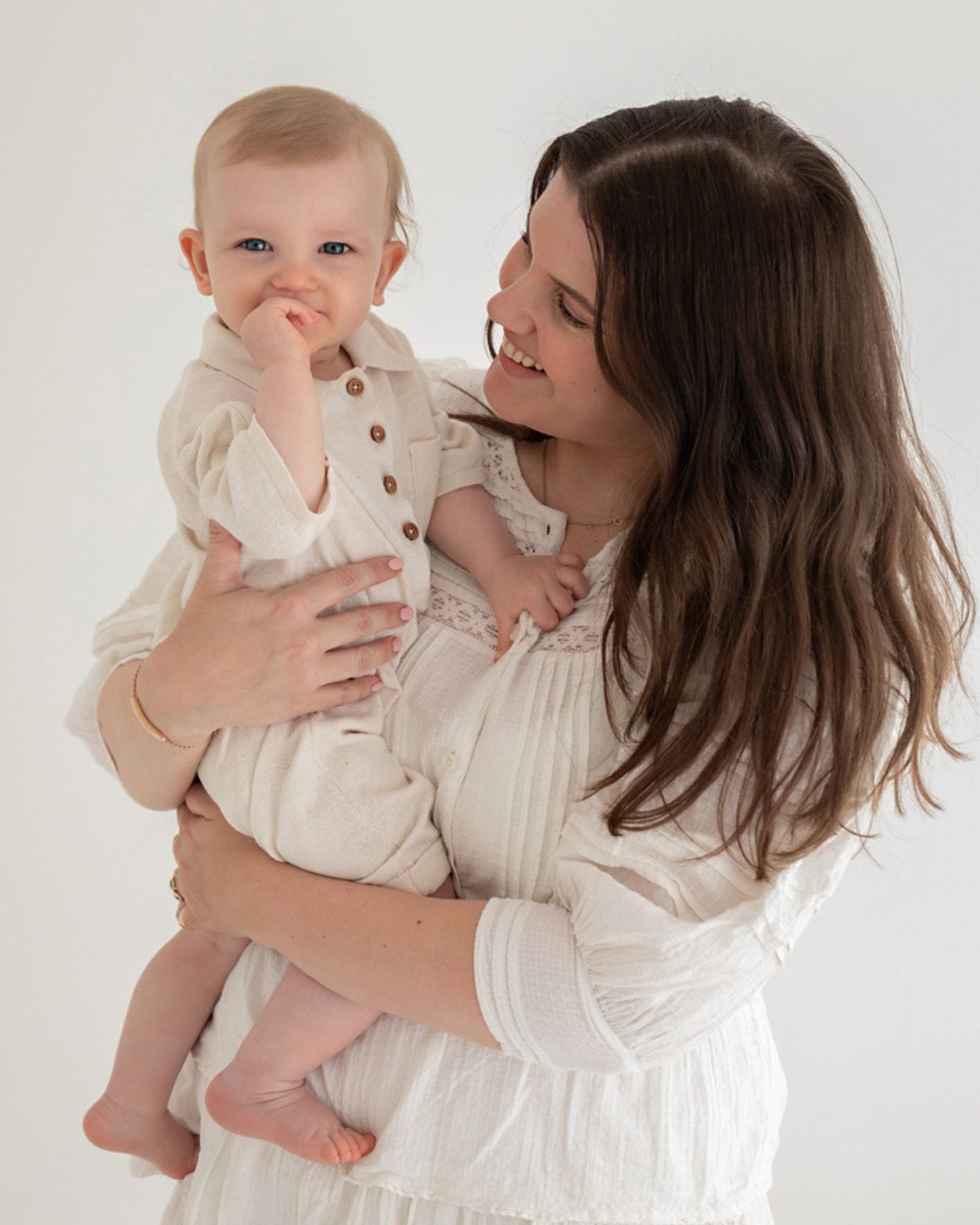 Mum holding baby in a calm studio setting by Photography by Valentina.