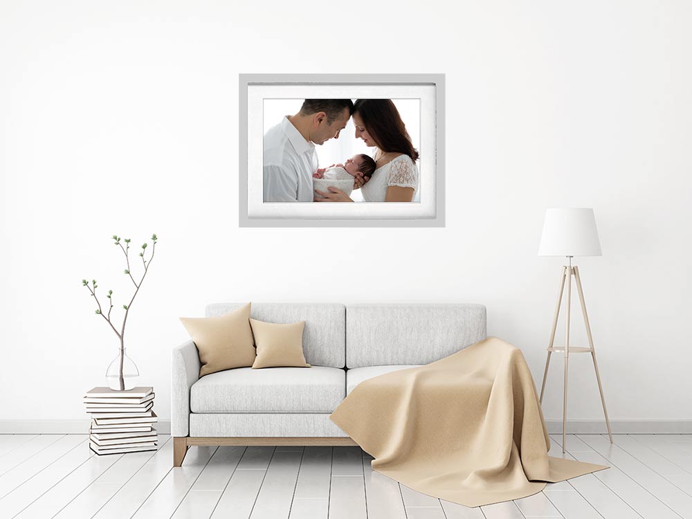 Framed newborn portrait displayed above a beige sofa – showcasing printed photography in a modern Richmond home by London newborn photographer Valentina.