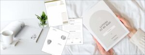 Flat lay of pregnancy and baby journal pages with a soft cup, flower vase, and hands holding the “Letters to My Baby” guide,  a gentle writing tool for expectant mums.